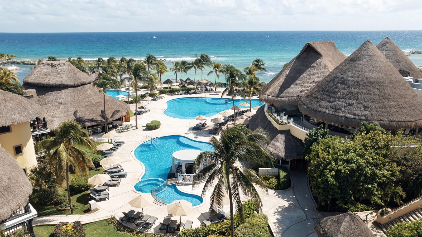 Palm-lined pools and palapa roofs by the sea at Catalonia Yucatan Beach